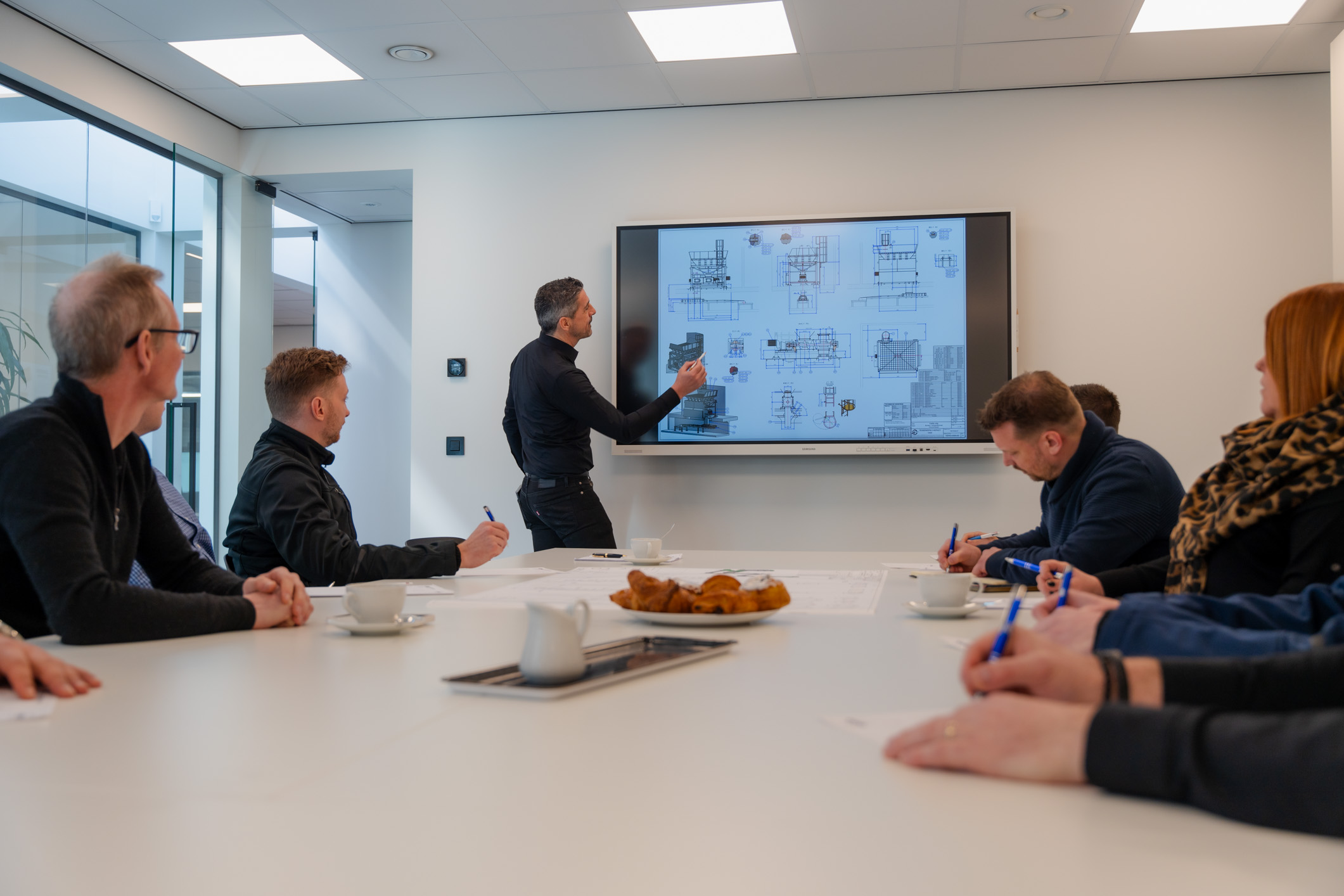 Een werkvoorbereider van Leenders nv presenteert technische tekeningen tijdens een meeting.